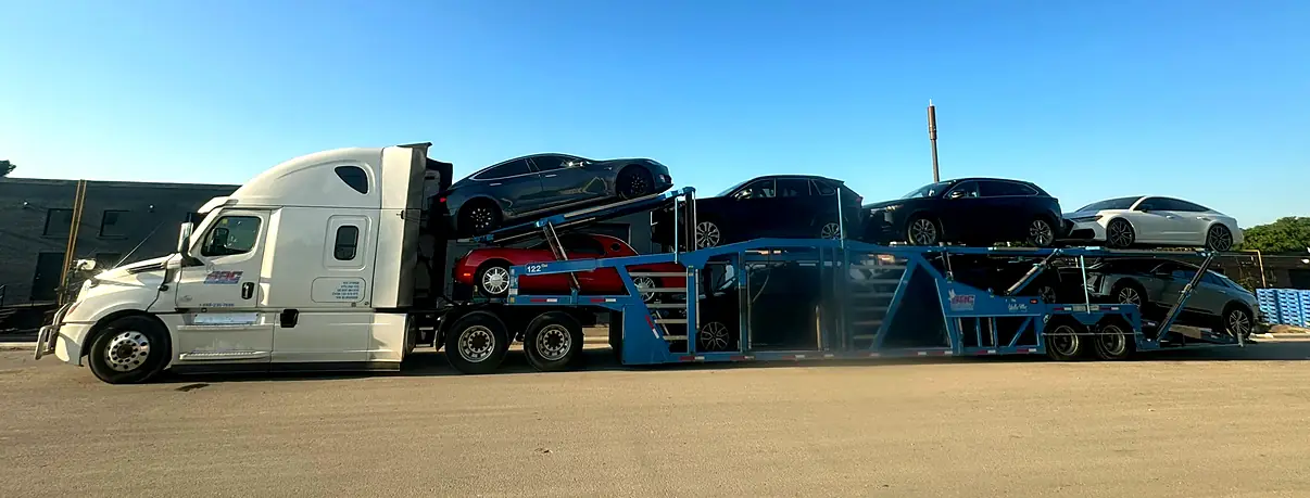 Fully loaded Snowbirds Auto Connection car carrier under a clear sky, every vehicle secured before departure