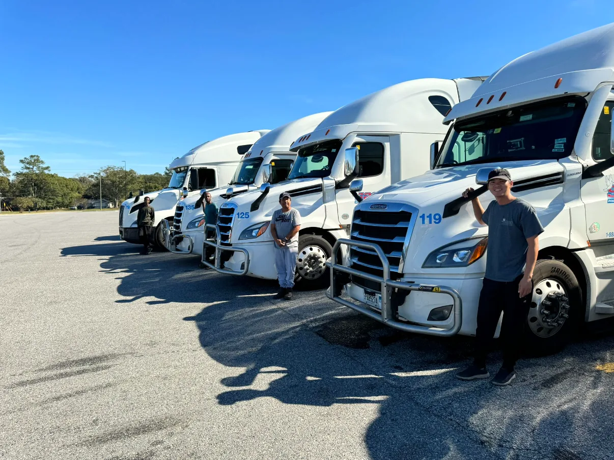 Snowbirds Auto Connection drivers standing with the company-owned car carrier trucks